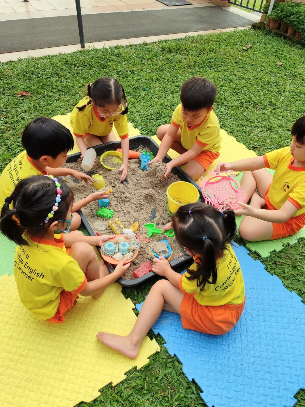 Children discovering sand and toys together outdoors.